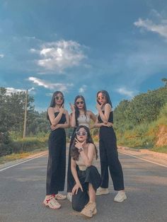 three women standing on the side of a road with their arms around each other, posing for a photo