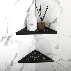 two black shelves with bottles and candles on them in a white marble bathroom wallpaper