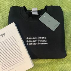 an open book sitting next to a black t - shirt with white writing on it