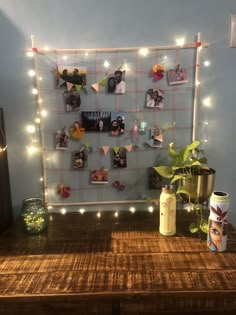 a wooden table topped with lots of pictures and string lights on the wall behind it