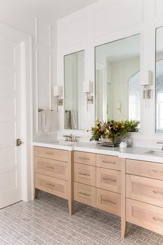 a bathroom with double sinks and large mirrors on the wall next to it's door