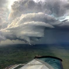 an airplane wing flying through a cloudy sky