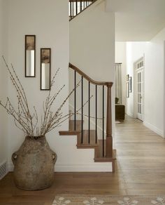 a vase with some flowers in it sitting on the floor next to a stair case