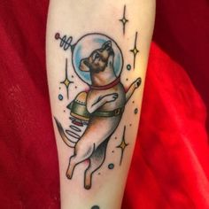 a dog in an astronaut's helmet tattoo on the right forearm and leg with stars around it