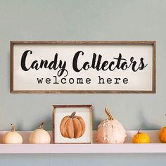 a sign that says candy collectors welcome here with pumpkins and gourds on the shelf