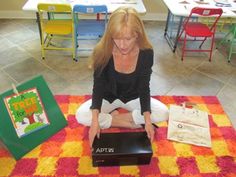 a woman sitting on the floor in front of a box with an open book inside