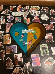 a heart shaped box sitting on top of a table covered in stickers