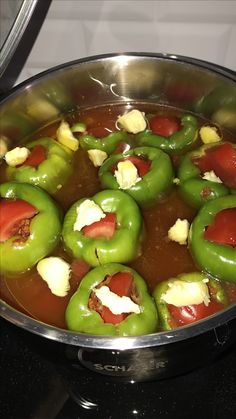 green peppers with tomatoes and cheese cooking in a pot on the stove top, ready to be cooked