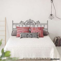 a white bed with pink and gray pillows