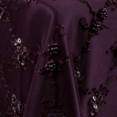 the fabric is very dark purple and has small flowers on it, along with beading