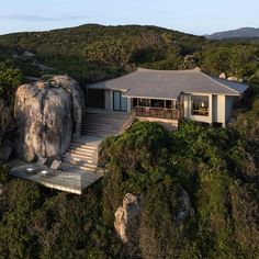 an aerial view of a house on top of a hill with trees and bushes surrounding it