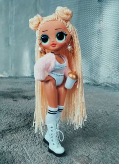 a doll with blonde hair and big eyes sitting on the ground