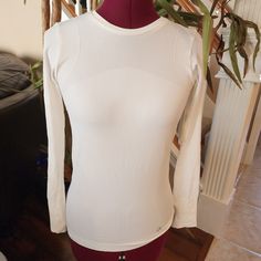 a woman's white top on a mannequin head stand in front of a plant