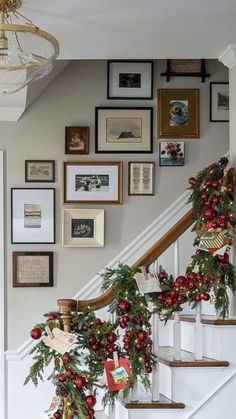 christmas decorations on the banisters and stairs are decorated with red berries, greenery and pine cones