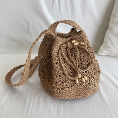 a crocheted bag sitting on top of a white bed next to a pillow