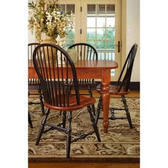 a dining room table with four chairs and a vase full of flowers on top of it