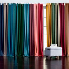 an open window with multicolored curtains and a footstool in front of it