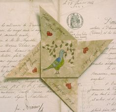 an origami bird with hearts on it's tail sitting on top of a piece of paper