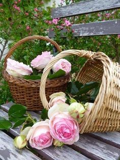 two wicker baskets filled with pink roses on a wooden bench