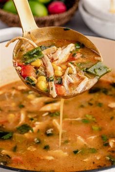 a wooden spoon full of soup being lifted from a pot with vegetables and meat in it