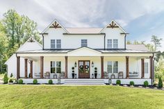 the front view of a white house with porches and columns on each side, surrounded by green grass