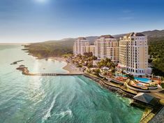 an aerial view of the resort and beach area at sunset, with sun shining over the water