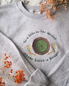 an embroidered sweatshirt that says it's a hole in the ground, there lived a hobbot