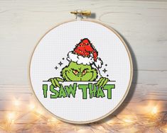 a cross stitch christmas ornament with the grin face and santa hat on it