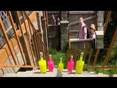 three bottles are sitting on the ground with straw hats and people standing in the background