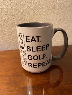 a coffee mug with the words eat, sleep, golf repeat on it sitting on a table