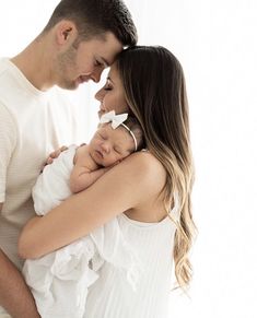 a man and woman holding a baby in their arms