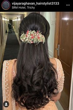 the back of a woman's head with long hair and flowers in her hair