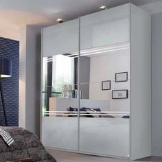 a bedroom scene with focus on the bed and mirrored closet doors that have been opened