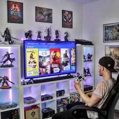 a man sitting in front of a flat screen tv holding a game controller and looking at it