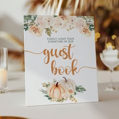 a sign that says guest book next to some wine glasses and candles on a table