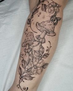 a tattoo on the leg of a woman with mushrooms and flowers