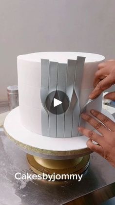 a person is decorating a cake with white frosting and silver decorations on it