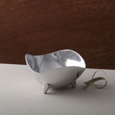 a silver bowl sitting on top of a table next to a leafy green plant