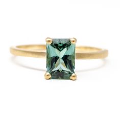 a gold ring with an emerald colored stone