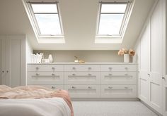 a bedroom with two skylights above the bed and dressers in front of it