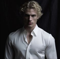 a man with blonde hair wearing a white shirt and black pants in front of a black background