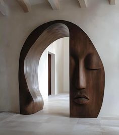 a large wooden sculpture sitting in the middle of a room next to an open doorway