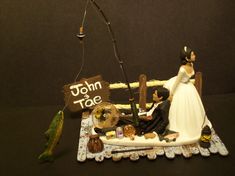 a wedding cake topper with a fishing hook and bride and groom figurines