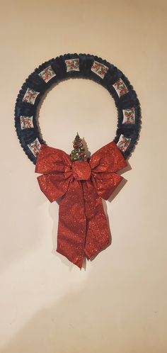 a christmas wreath with a red bow hanging from it's side on a wall