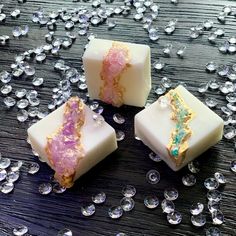 three pieces of soap sitting on top of a table covered in crystal stones and beads