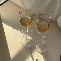 two wine glasses sitting next to each other on top of a white tablecloth covered floor