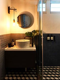 a black and white tiled bathroom with a round mirror on the wall above the sink