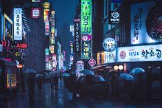 people with umbrellas walking in the rain on a city street at night under neon signs