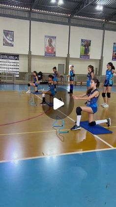 a group of girls in blue uniforms on a basketball court with one girl holding a ball