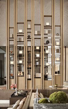 a living room filled with lots of furniture next to a tall wooden book shelf covered in books